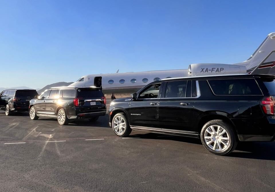 camionetas de lujo en pista de aeropuerto, junto a jet privado, listas para traslado de pasajeros